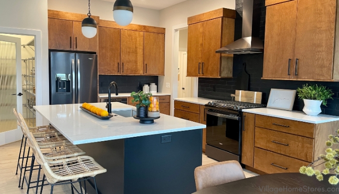 Kitchen design in Bettendorf Iowa with medium birch wood tone cabinets and black painted island. Black stainless appliances and black and brass pendant lighting also featured.