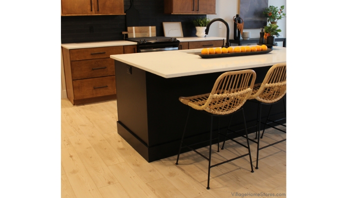 black painted kitchen island with white quartz countertops and woven barstools