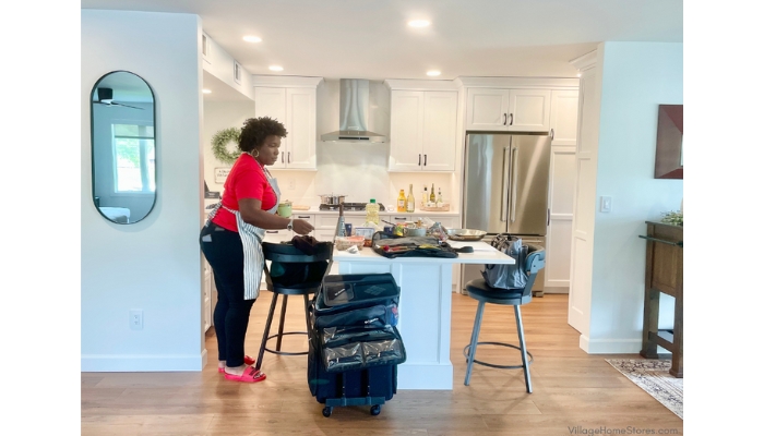 image of private chef KC Ross in a white painted kitchen with stainless steel appliances and small kitchen island.