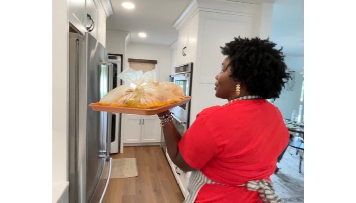Chef Keys KC Ross carrying tray of seafood boil bags to kitchenaid wall ovens in a Village Home Stores kitchen