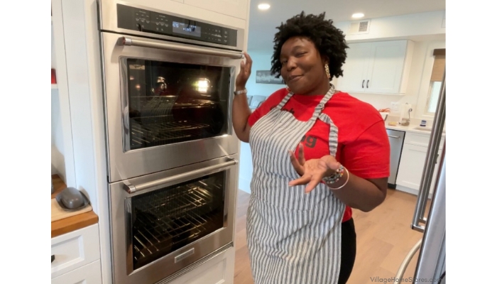 Chef Keys holding top handle of a double KitchenAid wall oven in Stainless Steel from Village Home Stores