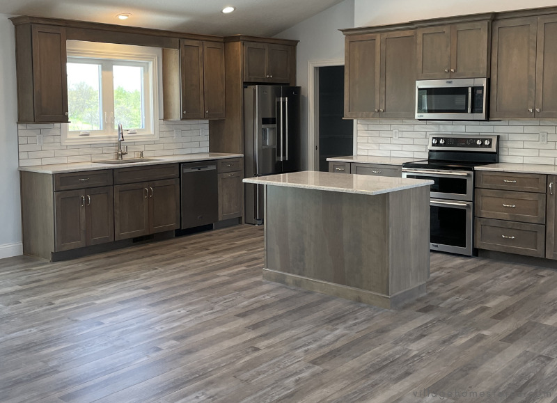 kitchen with small island in warm gray drift stain on birch wood cabinets from Koch cabinetry