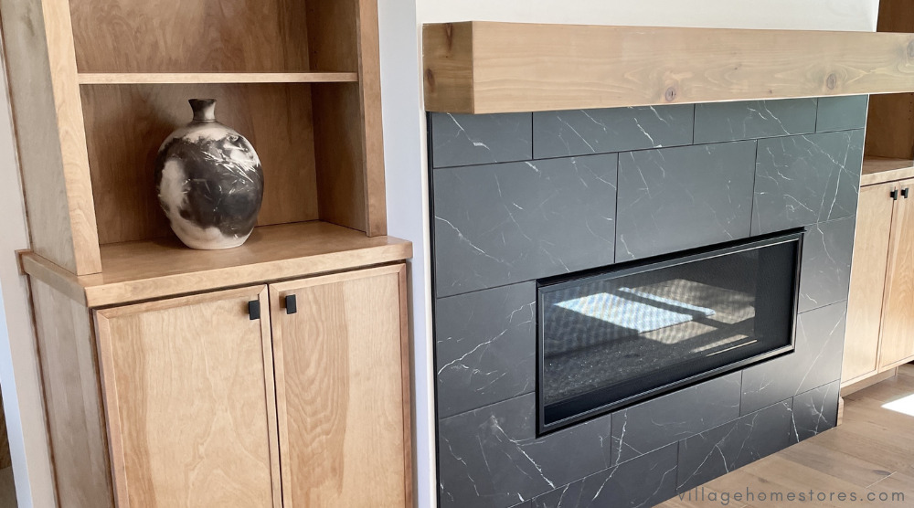 modern fireplace surround with black tiles around firebox and built in wood cabinetry on the side