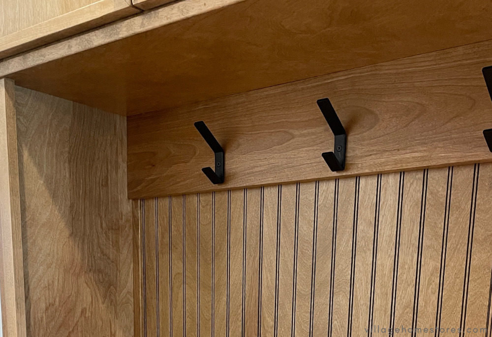 close up of coat hooks and beadboard paneling on drop zone bench