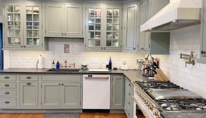 kitchen sink wall of amish cabinetry in sage green painted finish with black granite counters and white subway tile