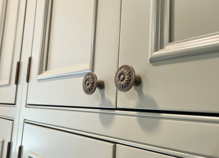 close up image of evergreen fog-painted inset cabinetry doors with beaded faceframe and brass knobs.
