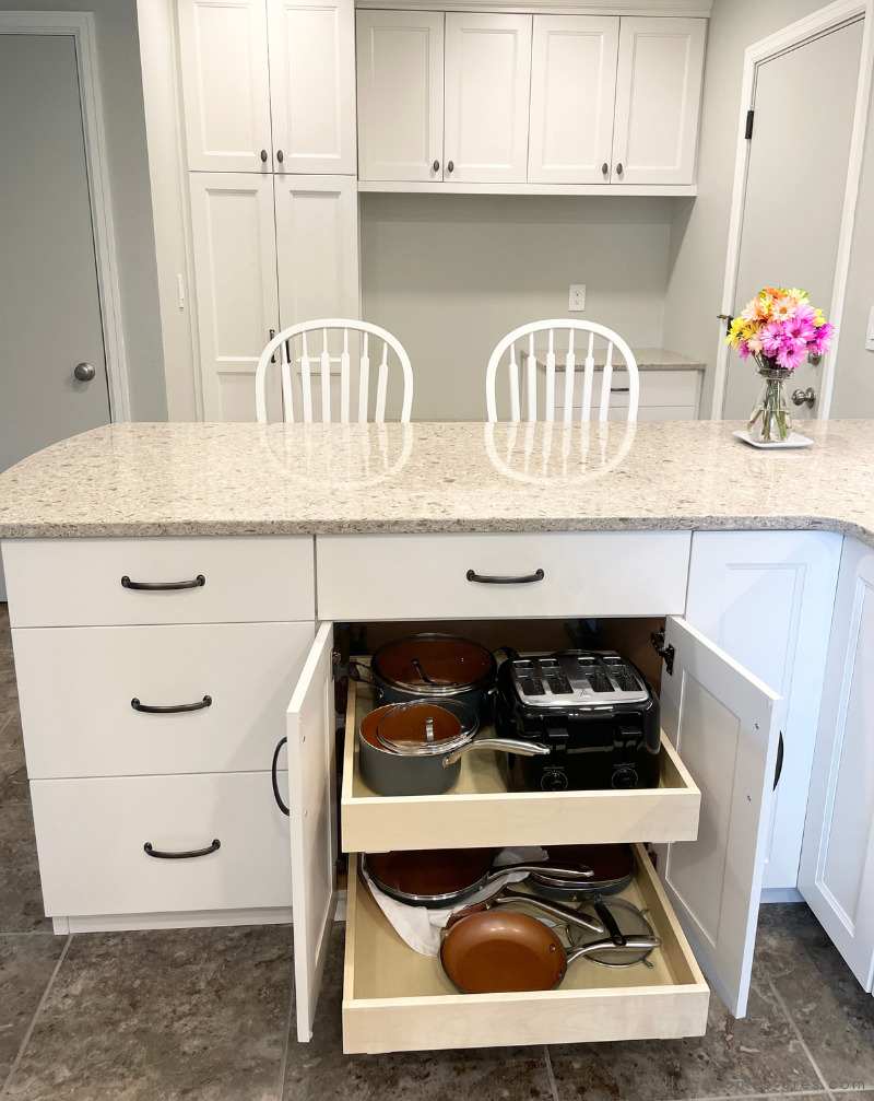 kitchen peninsula with white cabinets and doors open showing slide out shelving inside of base cabinet