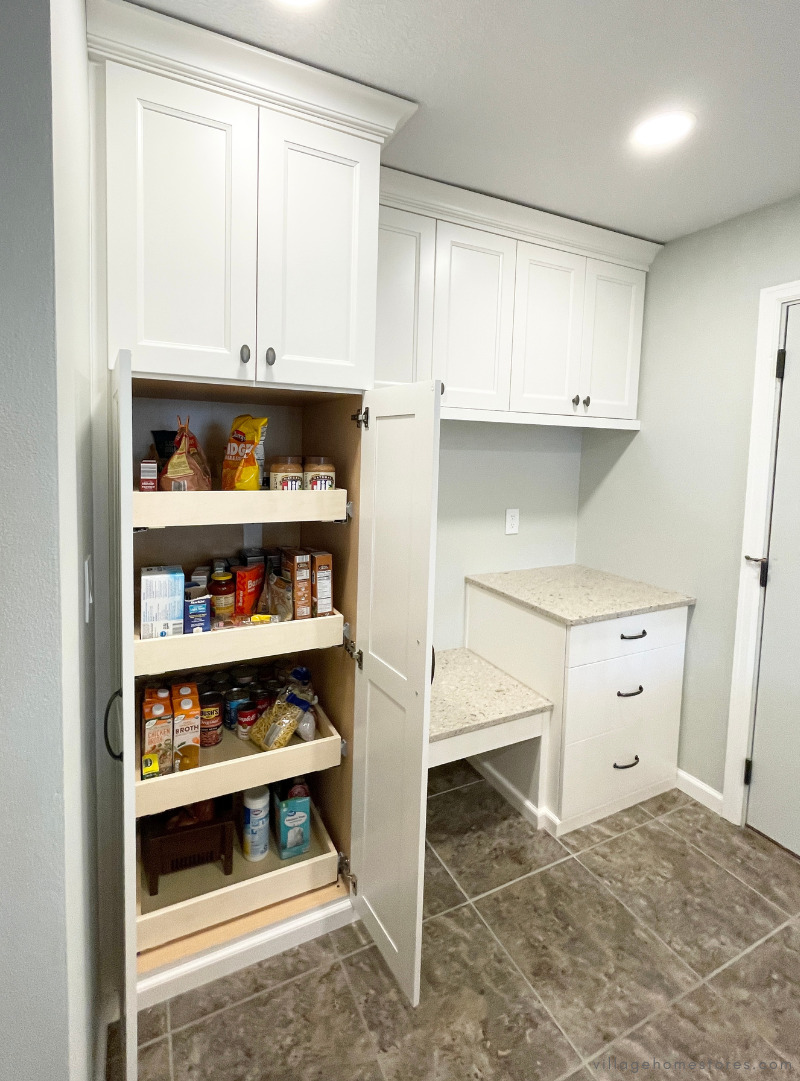 kitchen drop zone bench with tall pantry cabinet shown with doors open and slide out shelves stocked inside