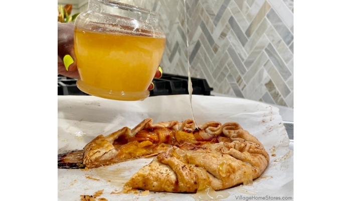 closeup shot of finished persimmon and plum galette with honey being drizzled on it