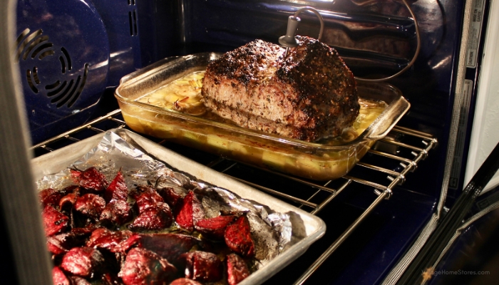kitchenaid wall oven with blue interior and rack of roasting beets and temperature probe plugged into wall and prime rib roast
