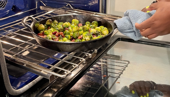 image of cast iron skillet with brussel sprouts being loaded into kitchenaid wall oven with blue interior