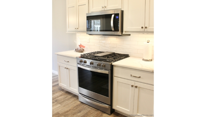 White cabinet kitchen with Whirlpool stainless steel gas range and over the counter microhood