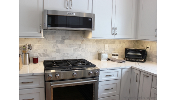 White cabinet kitchen with stainless steel range and low profile microwave hood installed above it