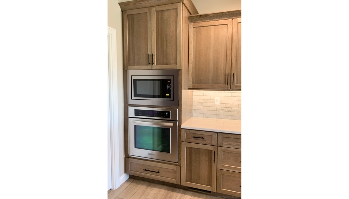 Warm gray stained kitchen with stainless wall oven and built in microwave installed