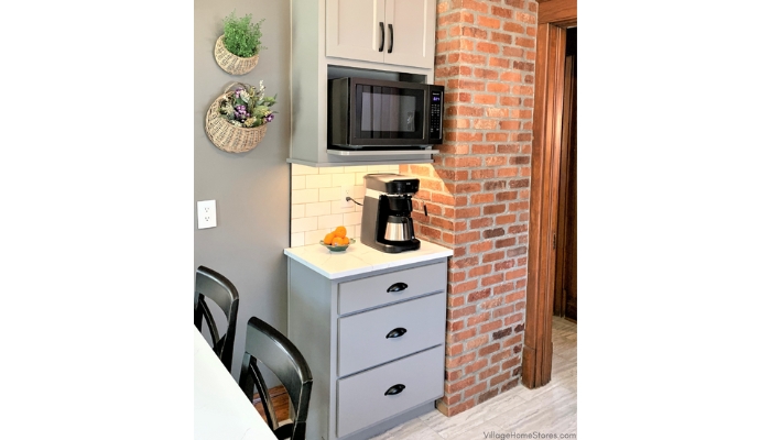 Kitchen coffee station with black coffeepot and microwave on wall cabinet shelf