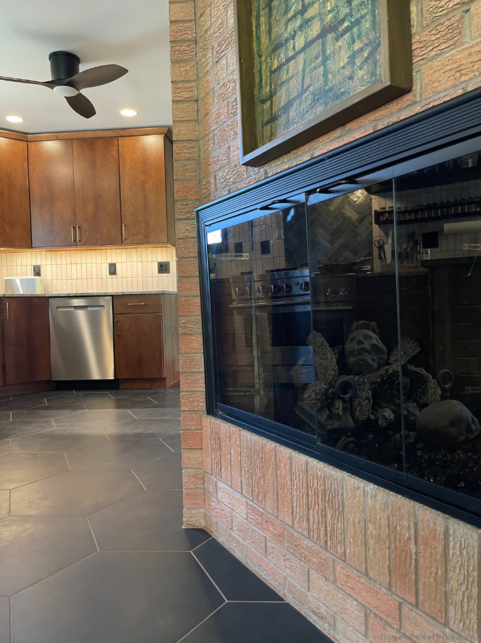 brick fireplace with skull firebricks in foreground and midcentury style kitchen in background
