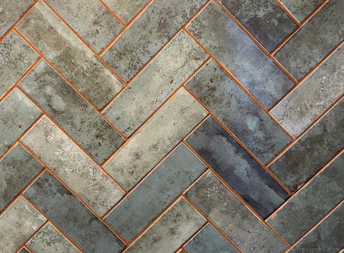 green glossy tonal backsplash tile installed in a herringbone pattern