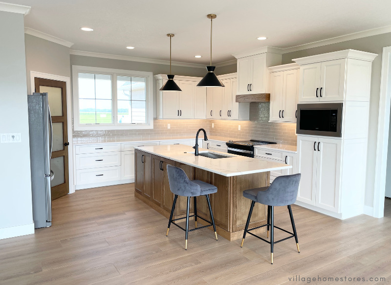 open concept great room kitchen design with white cabinets and white oak kitchen island with seating and black pendant lights above
