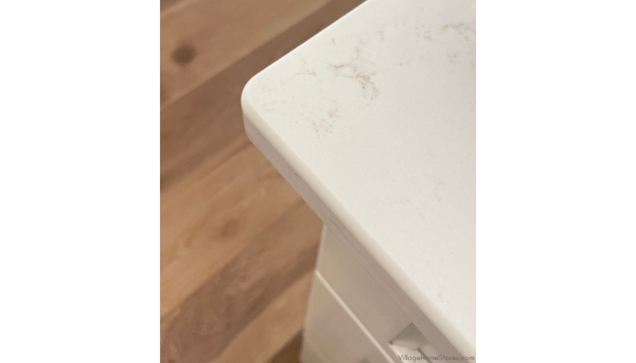 Kitchen countertop corner detail image of q quartz surface in an eased edge profile and carrara breve design.