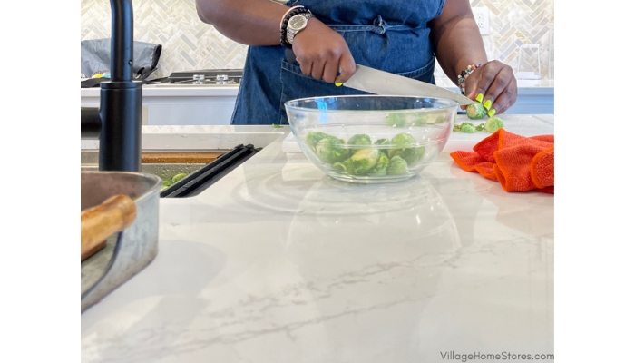 Chef Keys working on prepping brussel sprouts in a kitchen with Ethereal Glow Silestone counters by Village Home Stores
