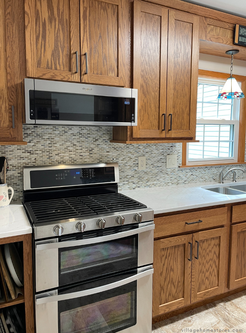 whirlpool appliances in an oak kitchen showing low profile microwave hood and double oven gas range