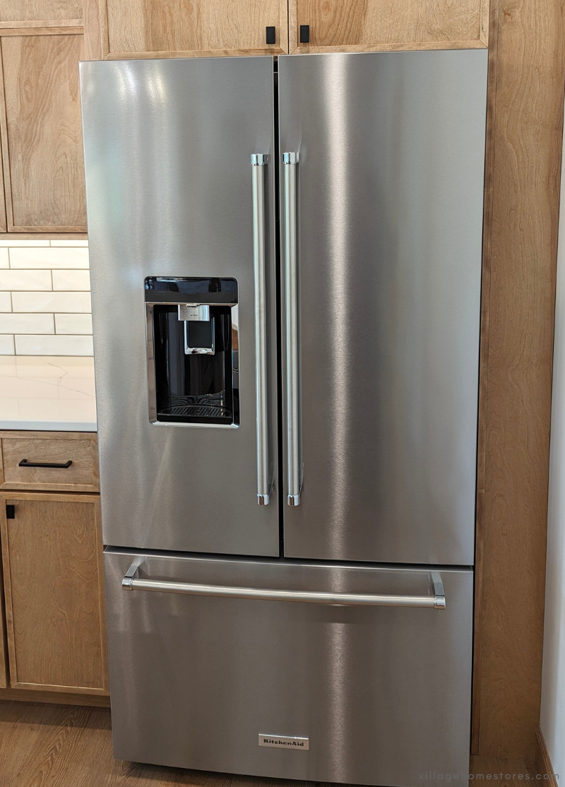stainless steel kitchenaid French door refrigerator installed in a medium wood kitchen
