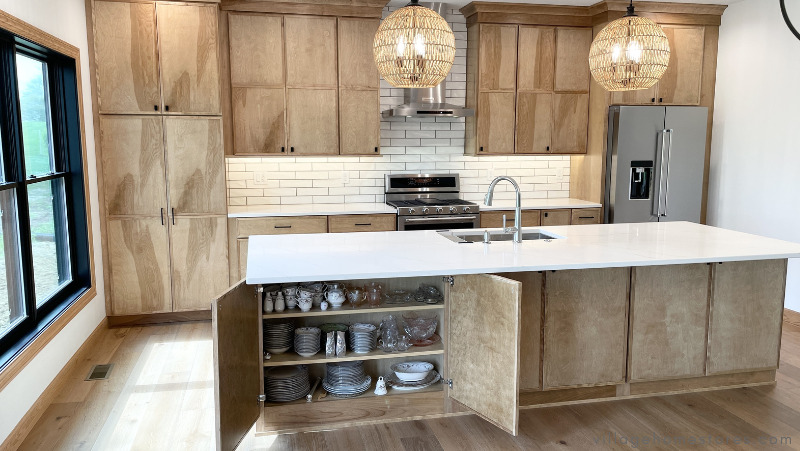 large kitchen island design with concealed storage on the back side showing doors open and shelves full of china