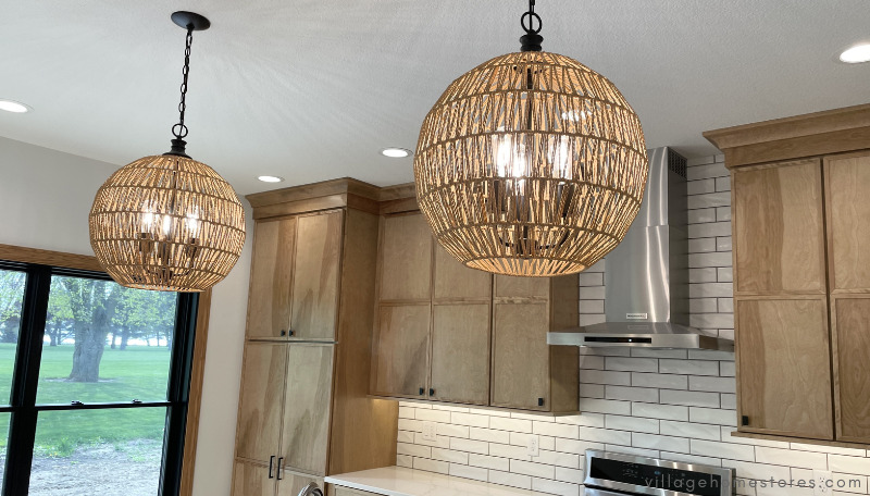 a pair of woven pendant lights hanging above a large kitchen island