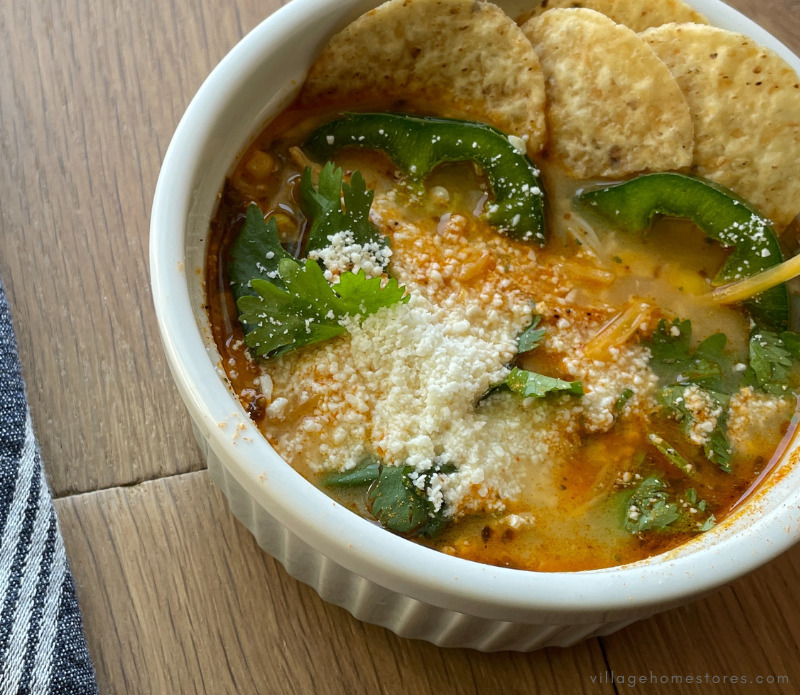 white ramekin os Mexican street corn soup with cheese, jalepenos, and tortilla chips for garnish