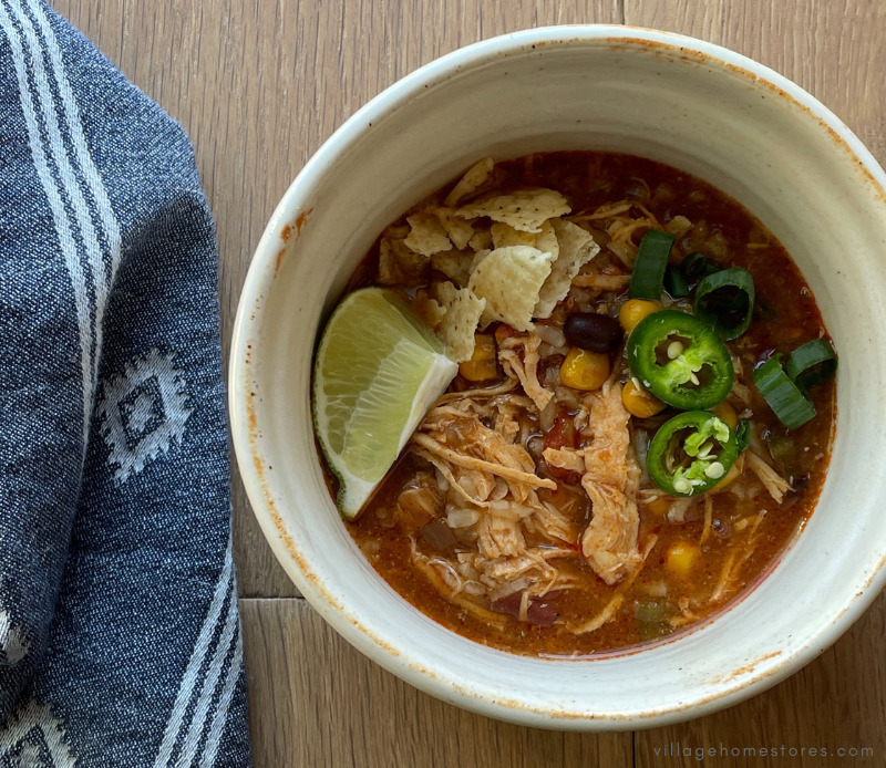 bowl of chicken tortilla soup with avocado, scallions, and tortilla chips for garnish
