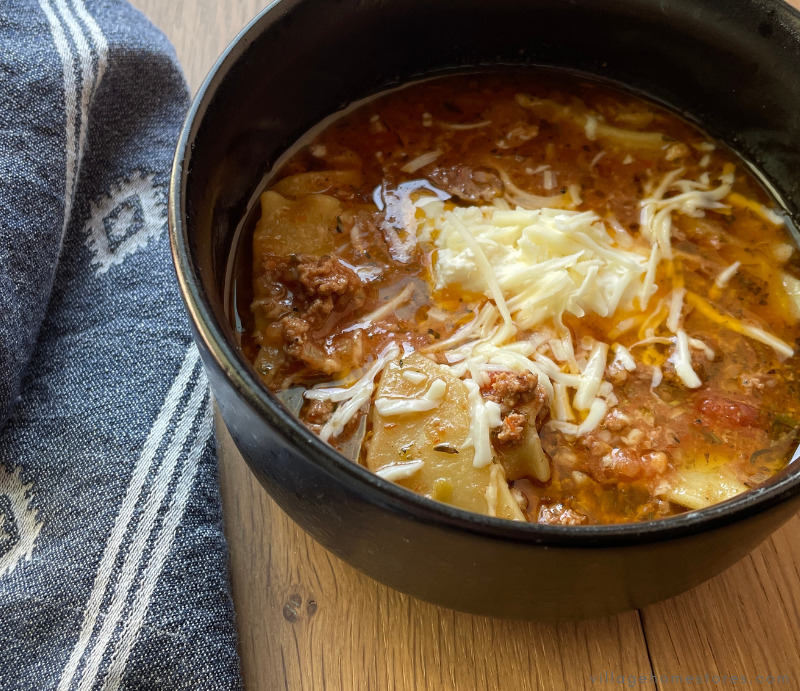 matte black bowl of lasagna soup with cheese as garnish