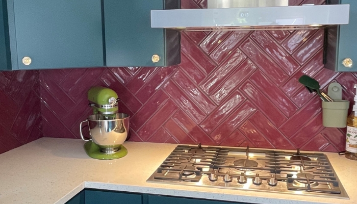 teal cabinet kitchen with long burgundy maroon wall tiles in herringbone pattern and bright green kitchenaid stand mixer