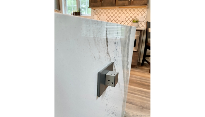 gray metallic finish square pop out outlet on side of kitchen island with waterfall end countertops