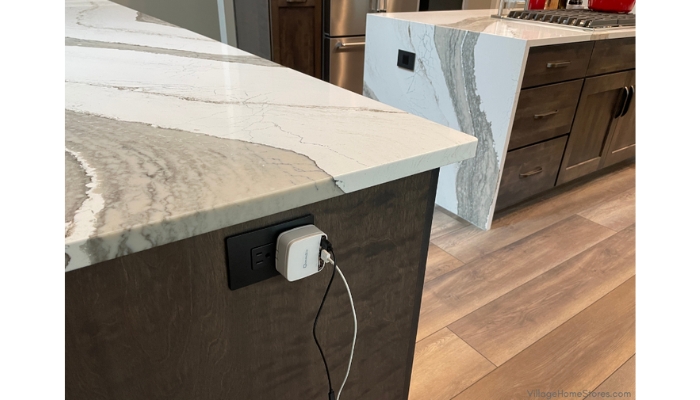 white charger plugged into outlet on the side of a kitchen cabinet island with view of second kitchen island in background