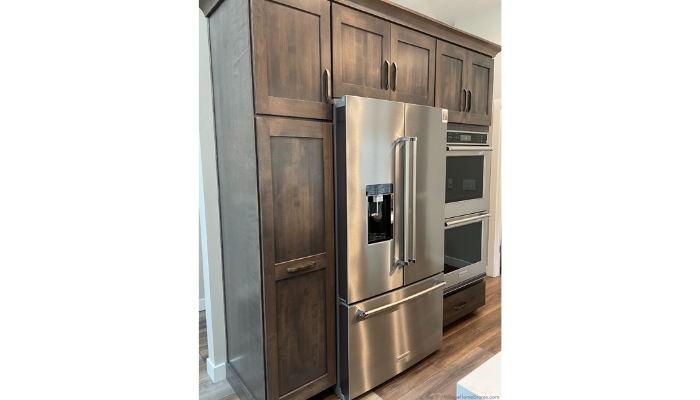 kitchen wall with tall pantry cabinet and stainless steel French door refrigerator and double wall oven