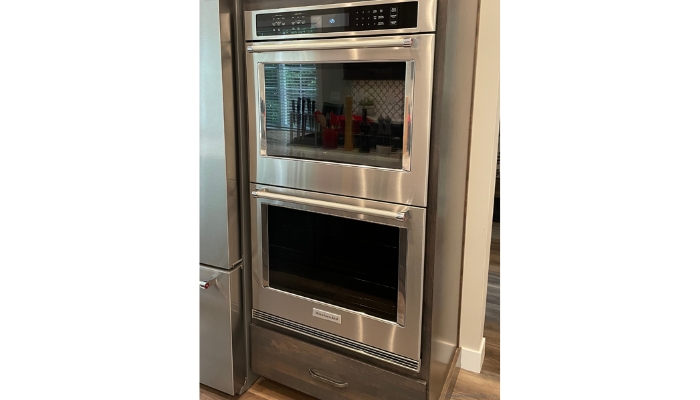 kitchen aid double wall ovens in stainless steel finish installed in a tall oven cabinet in gray stain