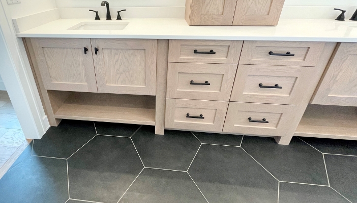 light oak bathroom vanities on black hex tiled floors