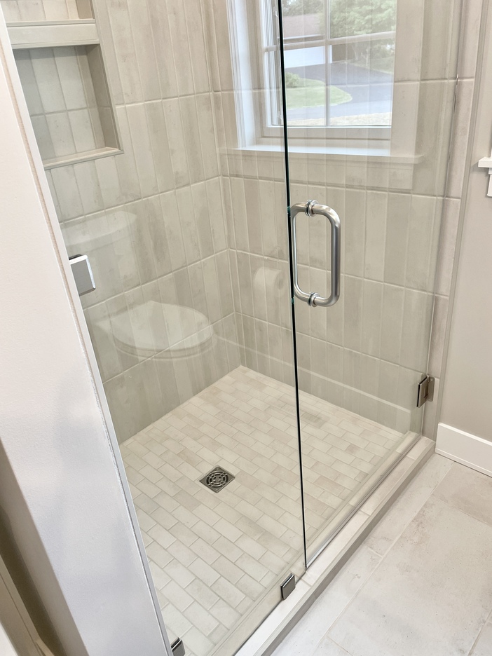 tiled shower with hinged shower glass door entry