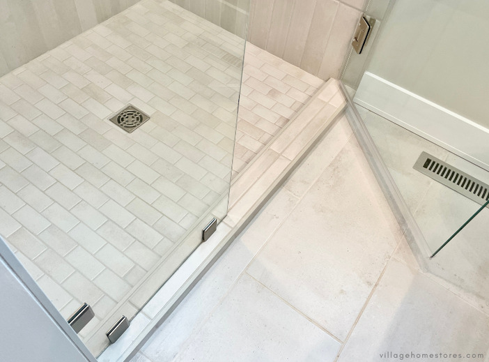 tiled bathroom floor and shower entry threshold with hinged glass door