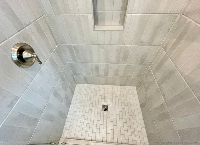 tiled shower with brick pattern floor and wall niche