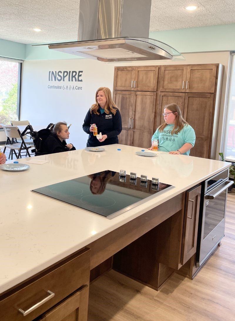 maytag electric cooktop in accessible roll up cabinet with stainless hood above and maytag wall oven in kitchen island