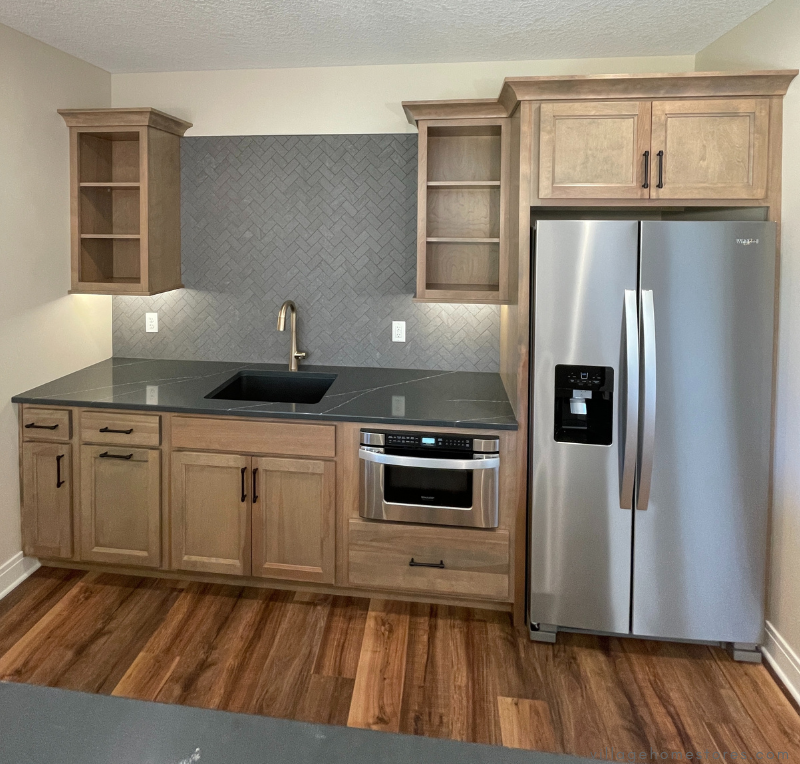 lower level bar cabinet design with sink, microwave, and refrigerator