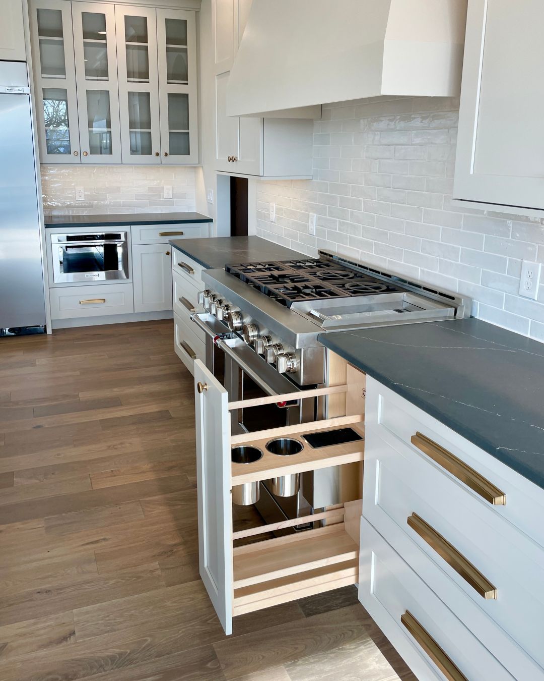 white cabinet kitchen with stainless range and utensil storage cabinet shown open