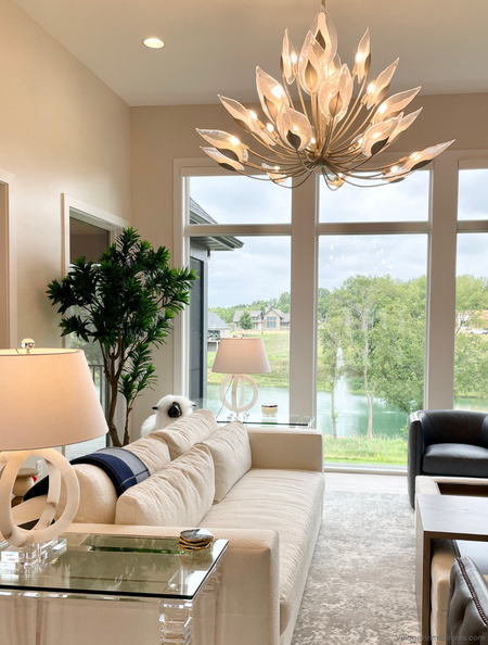 styled living room with white furniture and large chandelier fixture hanging
