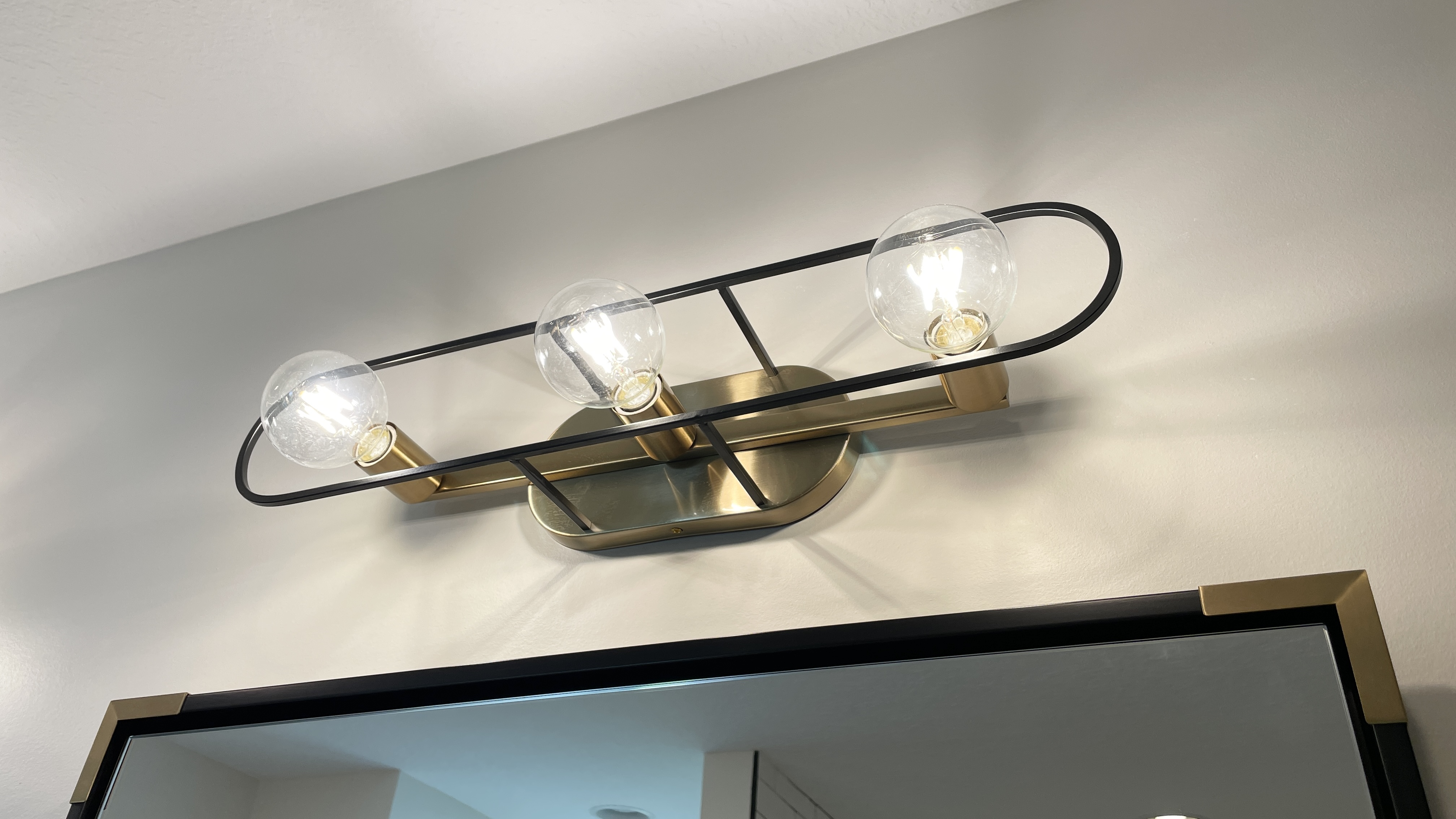 Midcentury Modern inspired bath vanity light with combination of black and brass finishes