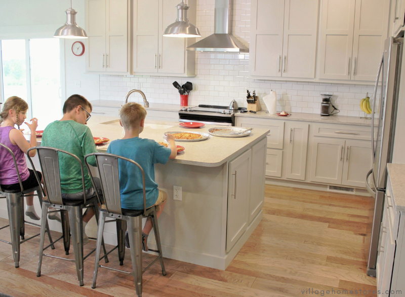 white cabinet kitchen with seating and three children eating