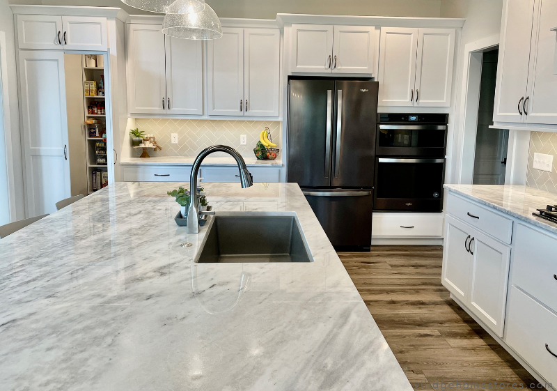 kitchen with white cabinets and black appliances and natural stone countertops with black undermount sink