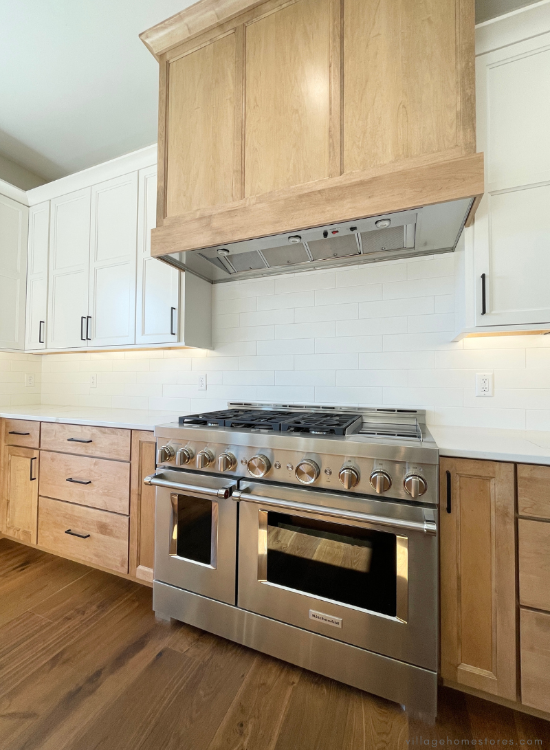 large commercial kitchenaid range with wood hood above