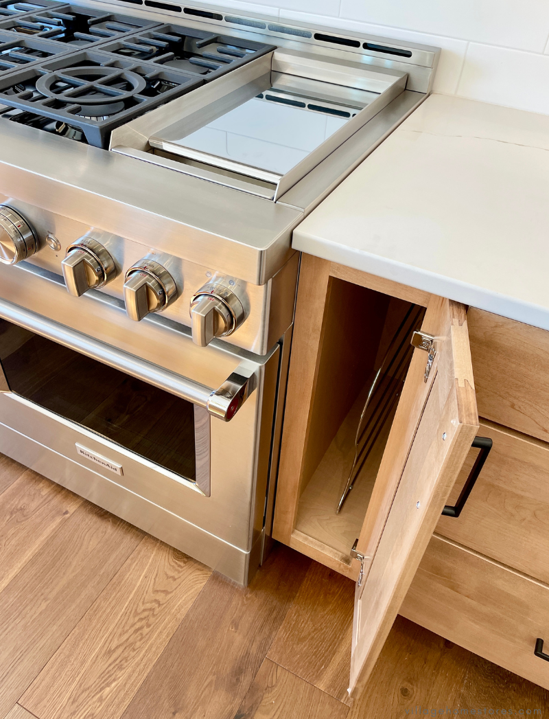 kitchen cabinets in maple pecan stain showing door open and tray storage near oven 