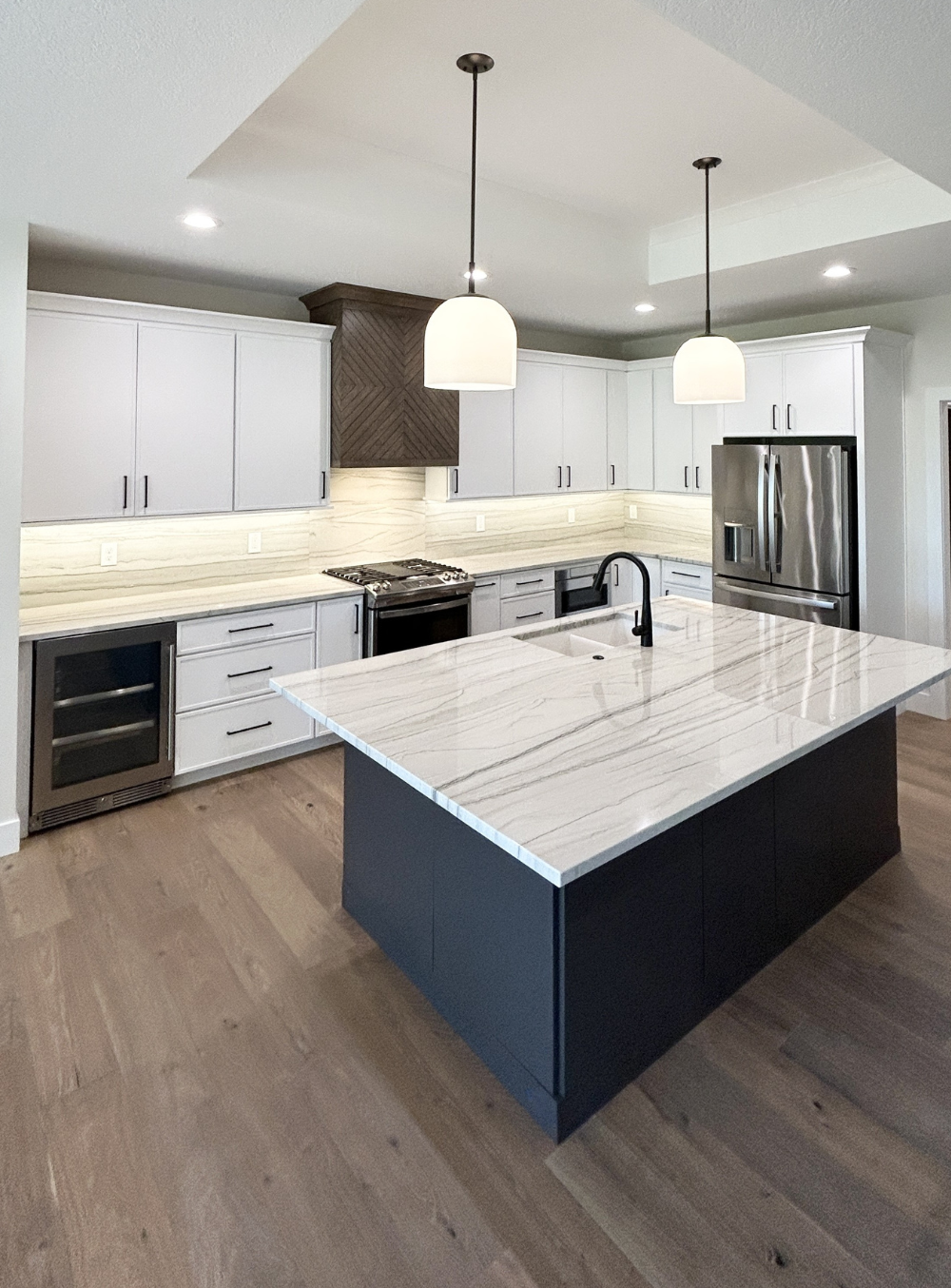 white and dark painted island kitchen design with tray ceiling above island and two pendants hanging
